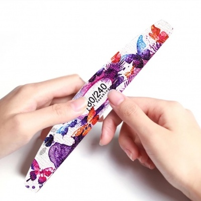 Lima de unhas colorida com padrão de borboletas e etiqueta 80/240 nas mãos