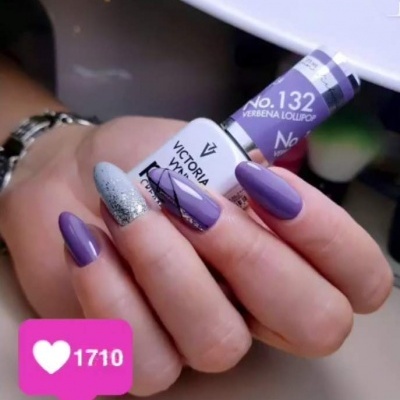 Unha pintada com verniz roxo e glitter prateado, segurando verniz Victoria Vynn