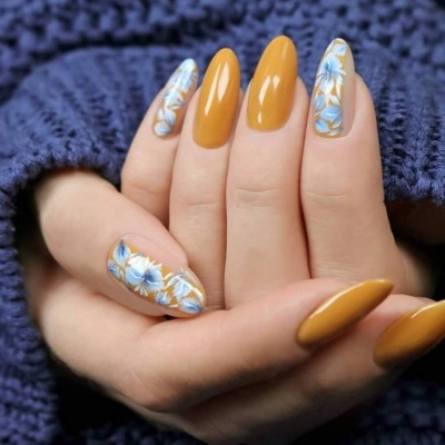 Unhas castanho-mostarda com decoração floral azul e branca