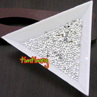 Prato triangular branco com contas prateadas sobre superfície de madeira escura