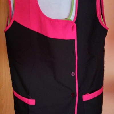 Colete bicolor preto e rosa com bolsos e botões pendurado em cabide