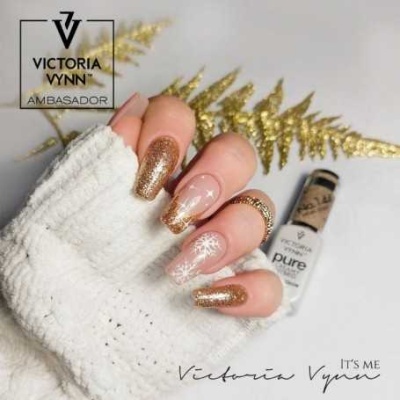 Mão com unhas decoradas em glitter dourado e estrelas, verniz Victoria Vynn ao fundo