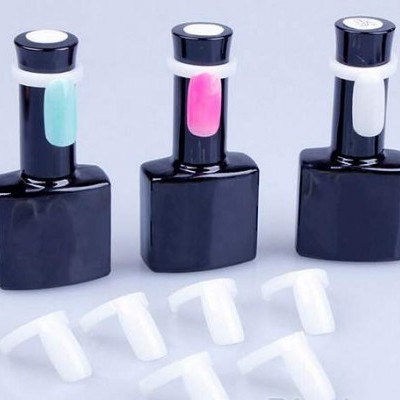 Três frascos de verniz com amostras coloridas e tampas brancas soltas