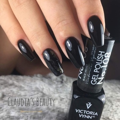 Mão com unhas pintadas de verniz gel preto brilhante segurando garrafa de verniz gel VICTORIA VYNN No. 108