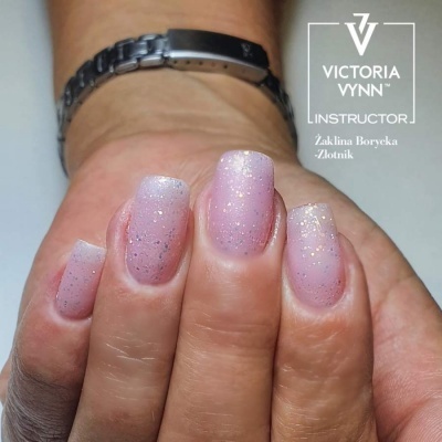 Mãos com unhas artificiais rosa claro com glitter e pulseira metálica preta e prateada