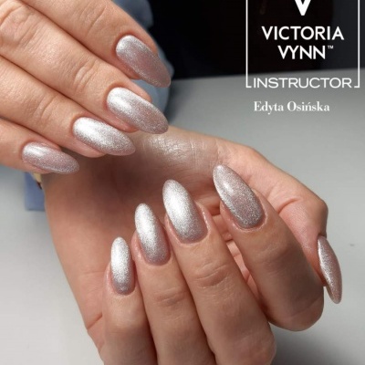 Mãos com unhas prateadas cintilantes e texto Victoria Vynn.