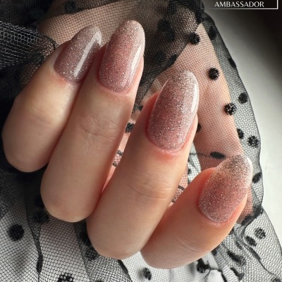 Unhas pintadas com verniz rosa brilhante sobre fundo de tule preto com pontos.