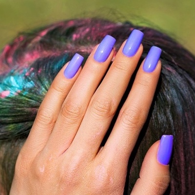 Mão com unhas roxas sobre cabelo colorido