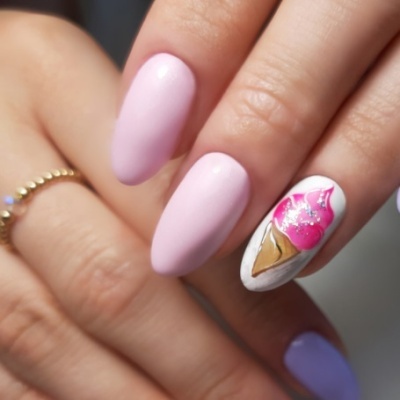 Unhas pintadas rosa e lilás com desenho de gelado numa unha, mão com anel