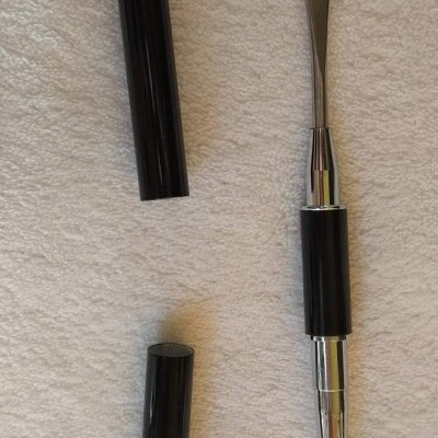 Aplicador de maquilhagem com espátula e pincel em fundo branco