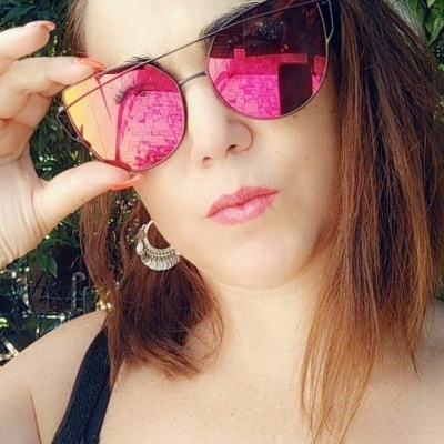 Mulher usando óculos de sol de armação preta e lentes rosas espelhadas em ambiente ao ar livre