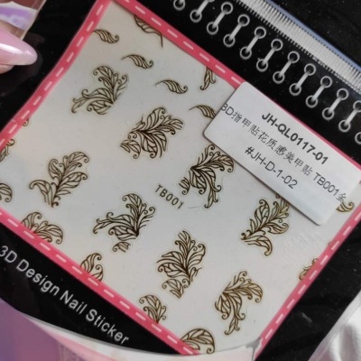 Adesivos para unhas 3D com padrões dourados em fundo branco em embalagem preta e rosa