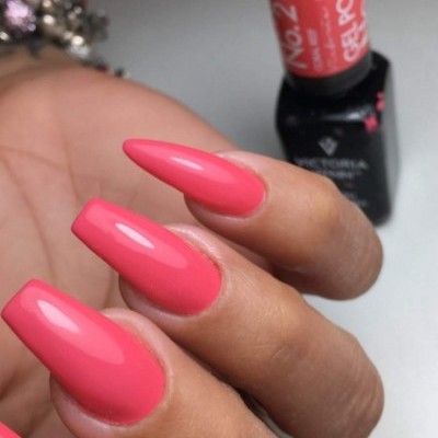 Unhas pintadas com verniz gel cor rosa com frasco de verniz ao fundo
