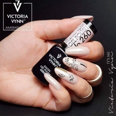Frasco de verniz gel Victoria Vynn numa mão com unhas decoradas nude e pretas