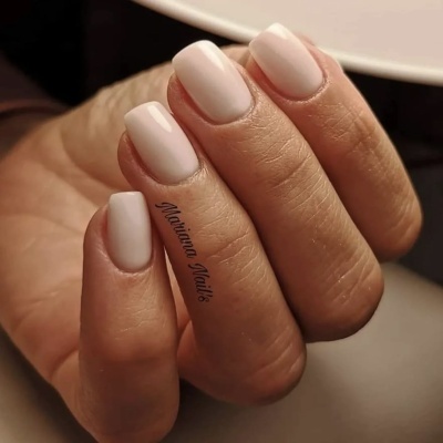 Mão feminina com unhas quadradas pintadas de cor creme