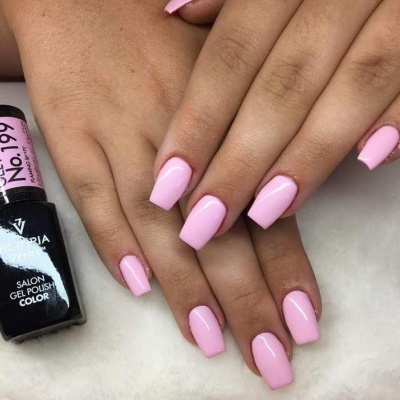 Mãos femininas com unhas pintadas de verniz gel rosa e garrafinha de verniz gel preto.