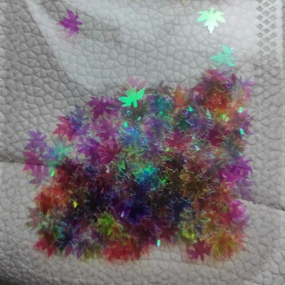 folhas decorativas holográficas coloridas sobre tecido branco texturizado