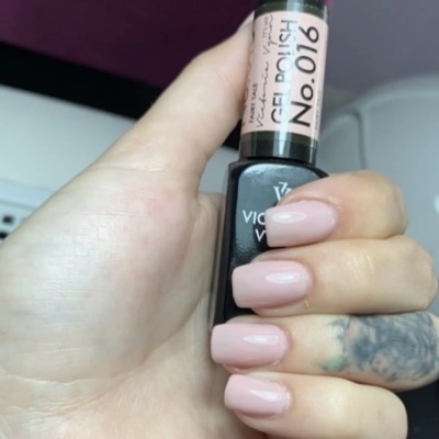 Mão com unhas em verniz nude segurando frasco de gel polish Victoria Vynn No.016