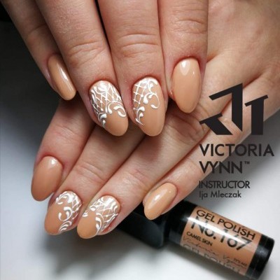 Unhas com verniz gel bege camel skin decoradas com arabescos brancos, frasco de verniz ao fundo com texto visível