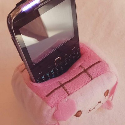 Telemóvel clássico preto em suporte de pelúcia rosa e branco em forma de animal