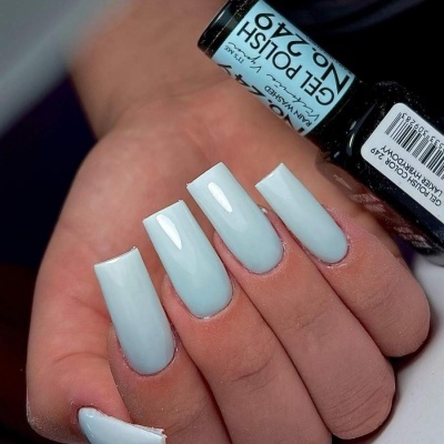 Mão feminina com unhas azuis claras e frasco de verniz Gel Polish nº 240