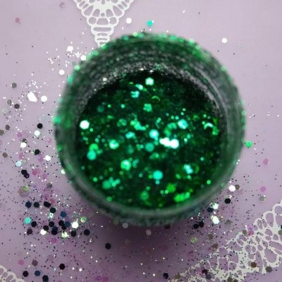 Frasco aberto de purpurina verde em fundo lilás com detalhes brancos