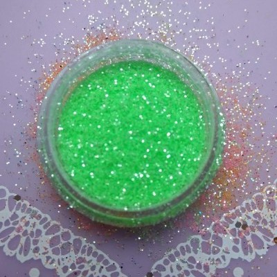 Frasco de glitter verde fluorescente em superfície lilás com brilho