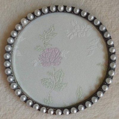 moldura circular com pérolas e padrão floral tecido