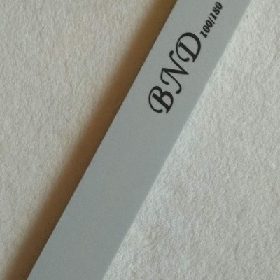 Lima de unhas cinzenta com texto BND 100/180 sobre fundo branco
