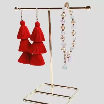 Suporte dourado com brinco vermelho e pulseira de contas