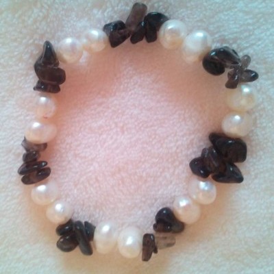 Pulseira de pedras pretas e pérolas brancas sobre tecido branco