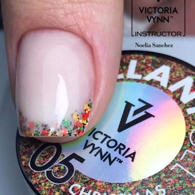 Unha com esmalte transparente e glitter colorido na ponta, sobre frasco de esmalte Victoria Vynn Christmas