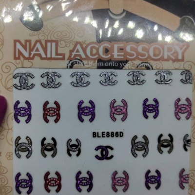 Acessórios para unhas com símbolos 'CC' em várias cores sobre cartão branco