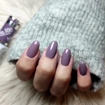 Mão com unhas roxas e manga cinza sobre fundo branco peludo