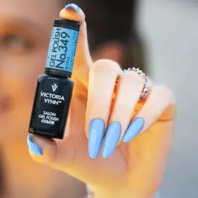 Mão segurando frasco de verniz gel azul claro, unhas pintadas combinando