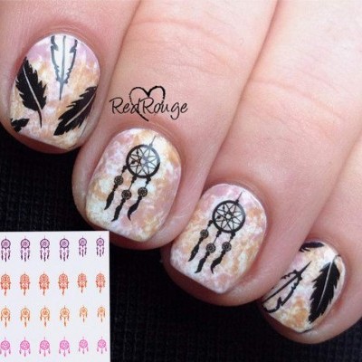 Unhas com decoração bege marmoreada e desenhos pretos de penas, flechas e filtro dos sonhos