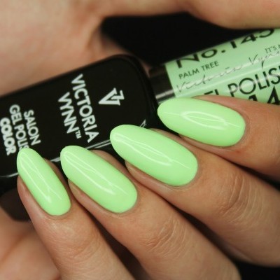 Unhas com verniz de gel verde claro segurando frascos de verniz preto e verde claro