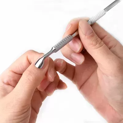 Mãos a usar ferramenta metálica texturizada para unhas com fundo branco