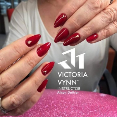 Mãos femininas com unhas vermelhas brilhantes e fundo rosa