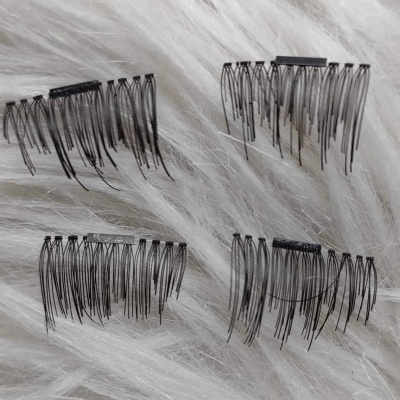 Quatro pentes de cabelo pretos pequenos sobre tecido branco felpudo