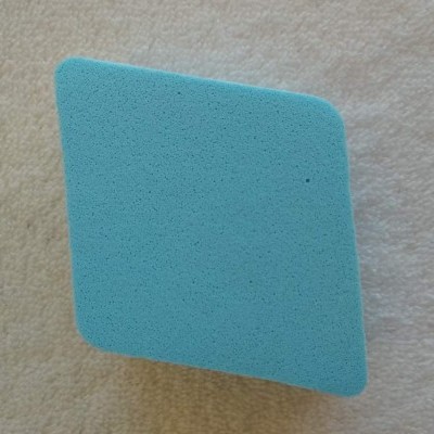 Espuma azul clara quadrada de maquilhagem sobre tecido bege