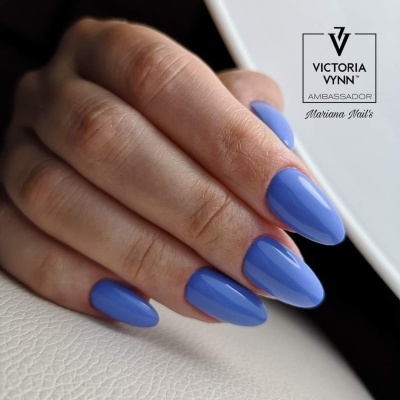 Unhas compridas pintadas de azul brilhante, texto Victoria Vynn Ambassador Mariana Nail's