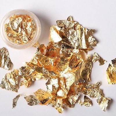 Flocos de folha dourada falsa e recipiente transparente com mais flocos