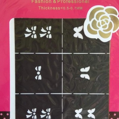 Embalagem cor-de-rosa de autocolantes para unhas com desenhos florais e de borboletas brancos em fundo preto.