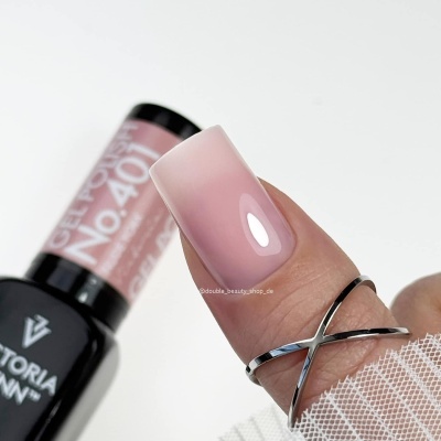 Unha com esmalte em gel rosa claro e anel em forma de cruz, junto a garrafa preta de esmalte com texto.
