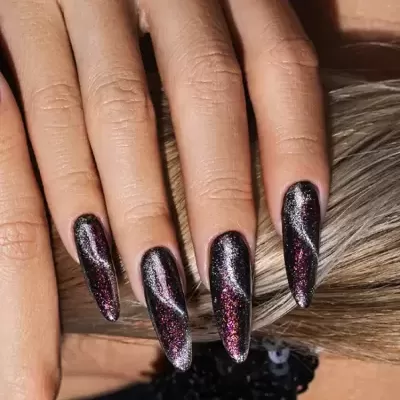 Unhas compridas com verniz preto e decoração holográfica em cabelo loiro.