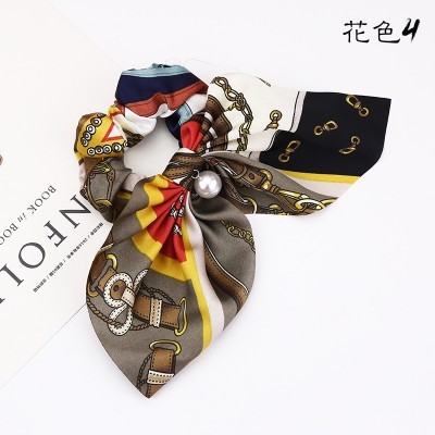 Lenço colorido com padrão de correntes, cintos e pérola decorativa.