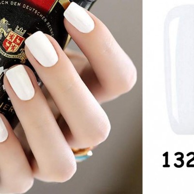 mão com unhas brancas segurando garrafa de cerveja com rótulo colorido e amostra de esmalte branco 1323