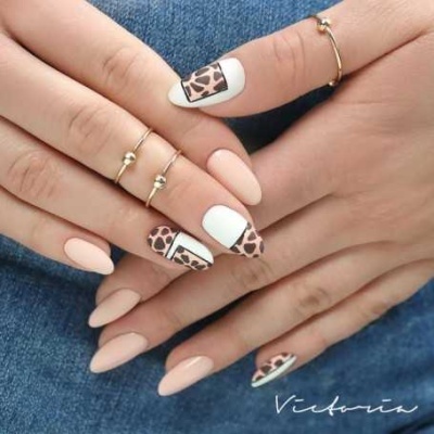Unhas postiças com design nude e padrão animal print em mãos femininas com anéis dourados
