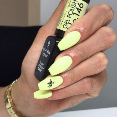 Mão com unhas amarelas e dois frascos de verniz gel